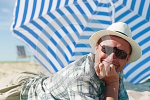 Man lying sand summer beach umbrella happy smile