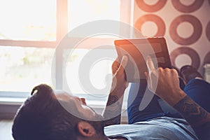 Man lying on sofa with digital tablet