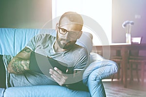 man lying on sofa with digital tablet