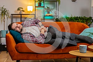Man lying on sofa feeling sudden strong abdominal stomach ache gastritis problem poisoning diarrhea