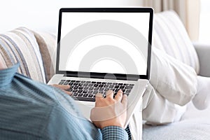 man lying on the sofa in the room and typing on a laptop keyboard