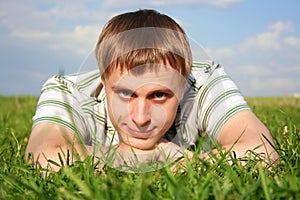 Man lying on summer lawn, chin on hands