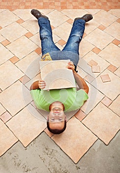 Man lying on unfinished floor tiling