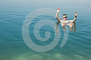 Man lying on water Dead Sea enjoying vacation in Jordan.Tourism recreation, healthy lifestyle concept. Copy space