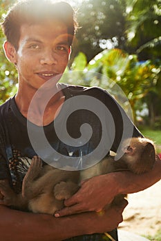 Man with macaque. A monkey keeper in Thailand holding his tame macque.