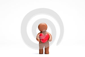 Man made from plasticine holding a heart on white background, aligned in the center