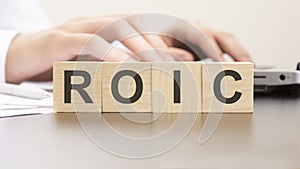 man made word ROIC with wood blocks on the background of the office table. selective focus. business concept.