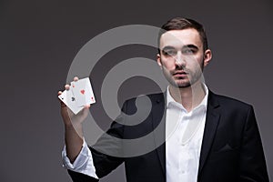 Man magician with two playing cards in his hand over grey background