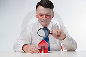 Man with a magnifying glass and paper house