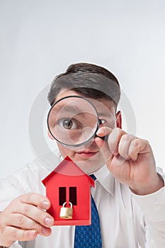 Man with a magnifying glass and paper house