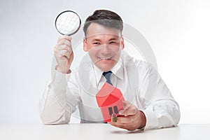 Man with a magnifying glass and paper house