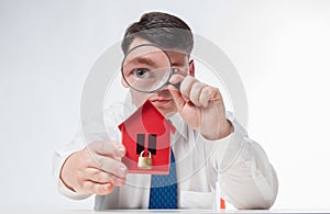 Man with a magnifying glass and paper house