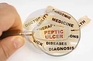 A man through a magnifying glass reads the inscriptions on scraps of paper, in the middle a red inscription Peptic ulcer