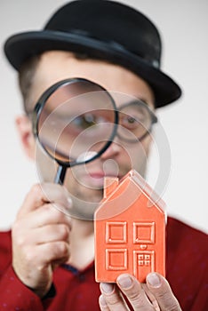 Man magnifying red house