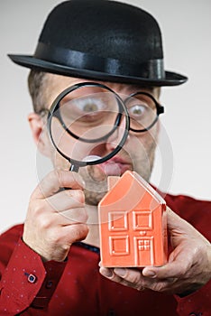 Man magnifying red house