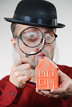 Man magnifying red house