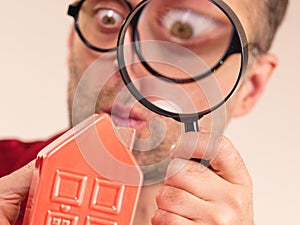 Man magnifying red house