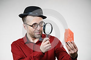 Man magnifying red house