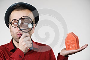 Man magnifying red house