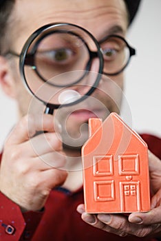 Man magnifying red house