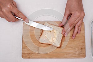 man makes a breakfast sandwich from white bread with butter