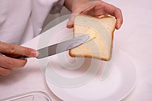 man makes a breakfast sandwich from white bread with butter