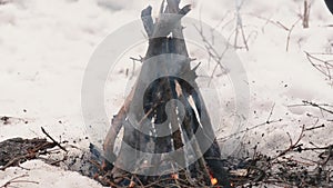 A man makes a campfire in the winter in a hike. Concept hike, walk, survival, trip in winter