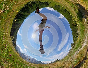 Man makes a jump in a mountain meadow. View from below. Daylight