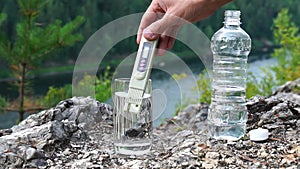 Man makes measurement of PPM salts in glass of clean water on mountain area. Theme of health and ecology. Slowmotion