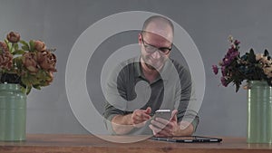 Man makes an order online by phone at a table on a grey background