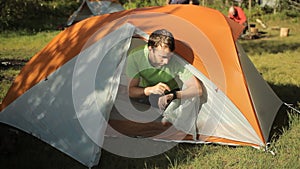 Man makes touch smartwatch out of the tent. Open the tent, touch screen and close the tent. Sunny day in the forest