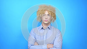 Man with makeup and a wig on a blue background . copy space