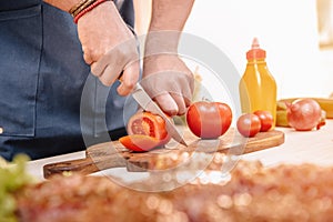 Man making burgers and cutting red tomatoes outdoors