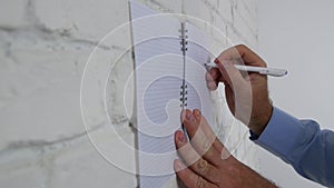 Man Making a Business Plan Drawing a Chart and Writing in Agenda on Office Wall