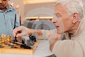 Man making chess move while playing at the game with his family