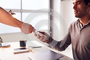 Man Making Contactless Payment Using Credit Card To Woman Holding Card Reader