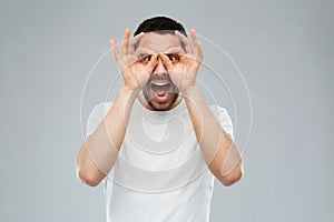 Man making finger glasses over gray background