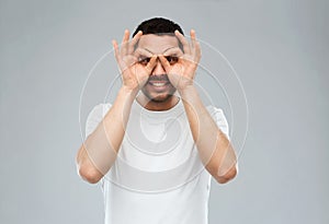 Man making finger glasses over gray background