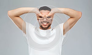 Man making finger glasses over gray background