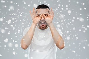 Man making finger glasses over snow background