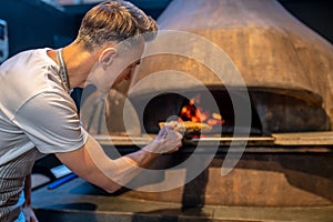 A man making fire in the oven in italian bakery