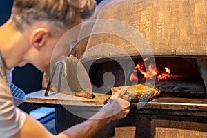 A man making fire in the oven in italian bakery