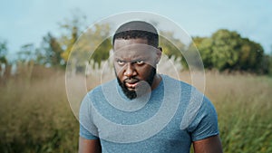 Man making grimaces on camera in park. Handsome sportsman standing outdoors