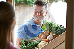 Man Making Home Delivery Of Organic Vegetable Box