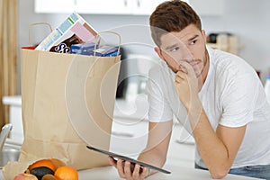 man making online purchase with tablet next to paper bag