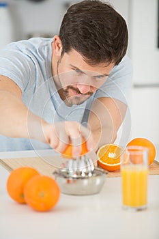man making orange juice in kitchen