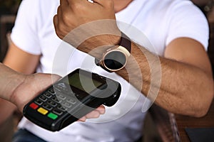 Man making payment with smart watch outdoors, closeup