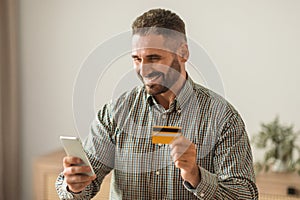 man making payments online with cellphone and credit card indoor