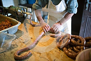 Man making sausages the traditional way using sausage filler.