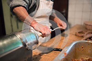 Man making sausages the traditional way using sausage filler.